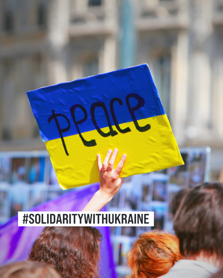 'solidaritywithukraine' hashtag on a picture of a protestan holding a banner that says 'peace'