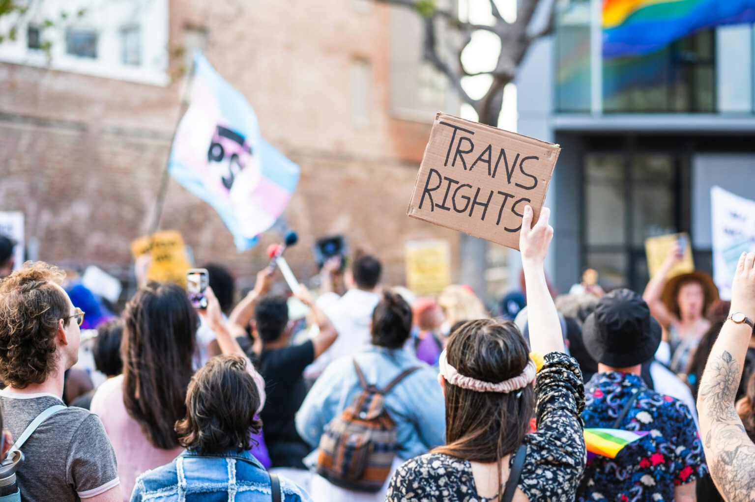 Crowd of demonstrators one holds up a sign which says 'trans rights'