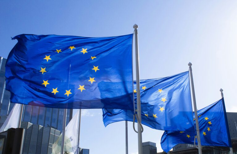 Three EU flags flying in a blue sky